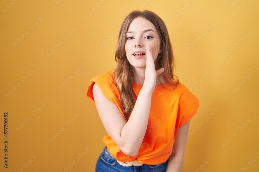 Caucasian woman standing over yellow background hand on mouth telling secret rumor, whispering malicious talk conversation Caucasian woman standing over yellow background hand on mouth telling secret rumor, whispering malicious talk conversation