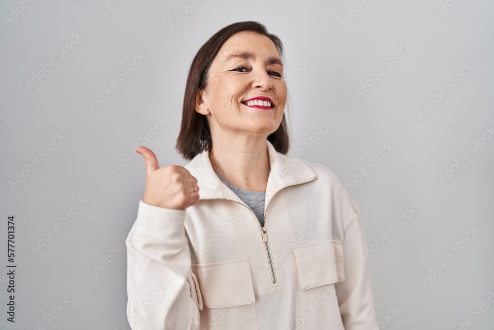Middle age hispanic woman standing over isolated background doing happy thumbs up gesture with hand. approving expression looking at the camera showing success. Middle age hispanic woman standing over isolated background doing happy thumbs up gesture with hand. approving expression looking at the camera showing success.