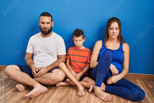 Family of three sitting on the floor at home skeptic and nervous, frowning upset because of problem. negative person.