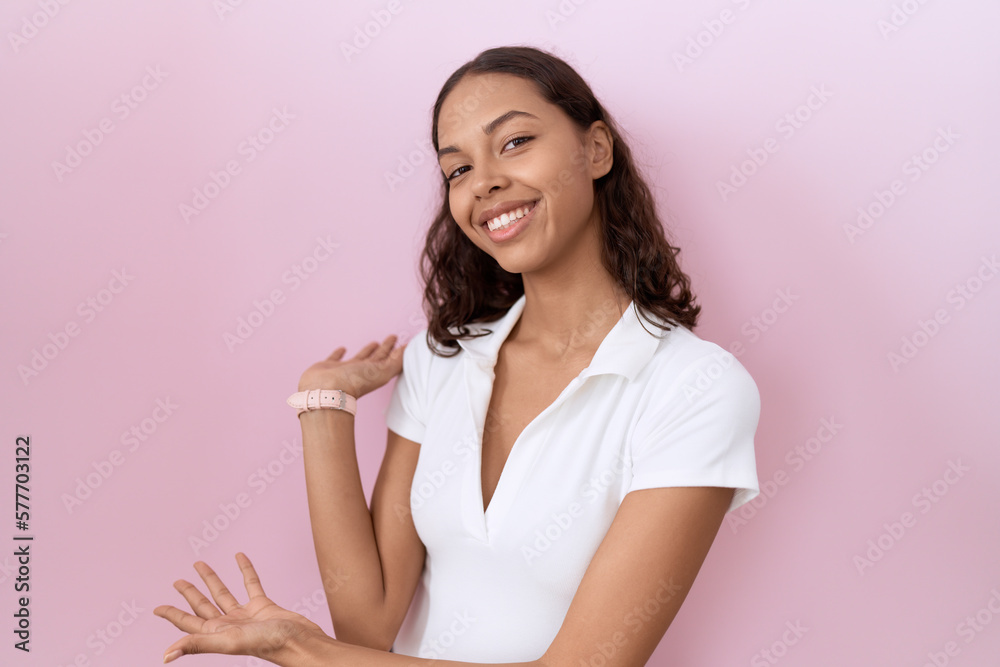 Young hispanic woman wearing casual white t shirt inviting to enter smiling natural with open hand Young hispanic woman wearing casual white t shirt inviting to enter smiling natural with open hand