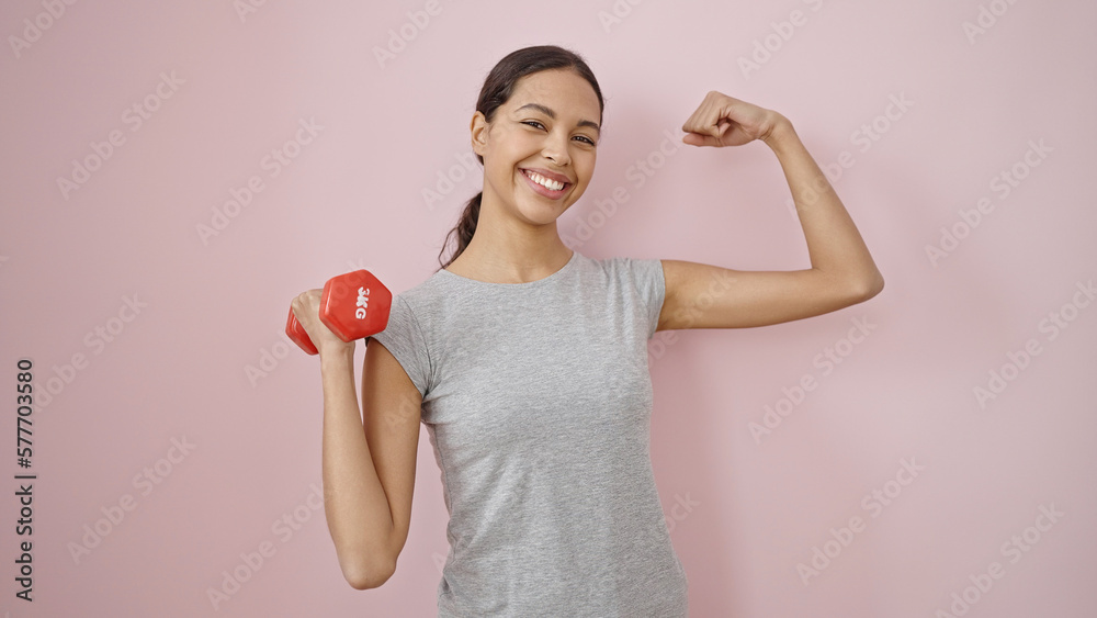 Young beautiful hispanic woman smiling wearing sportswear showing arm muscles over isolated pink background Young beautiful hispanic woman smiling wearing sportswear showing arm muscles over isolated pink background