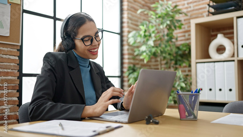 Young beautiful hispanic woman business worker using laptop wearing headset at office