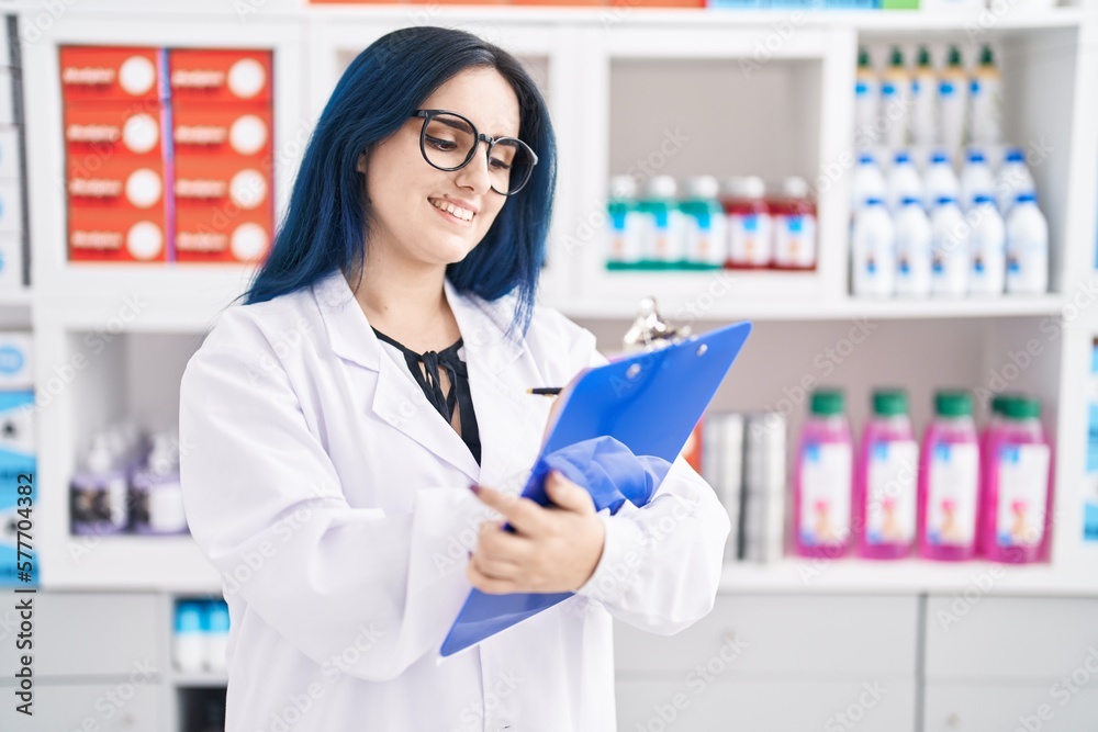 Young caucasian woman pharmacist smiling confident writing on document at pharmacy
