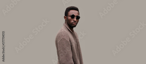 Portrait of stylish young african man model wearing knitted cardigan isolated on gray background