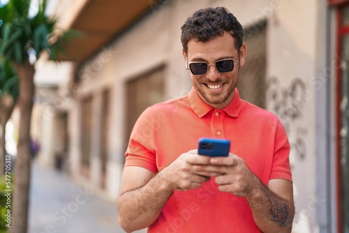 Young hispanic man smiling confident using smartphone at street © Krakenimages.com