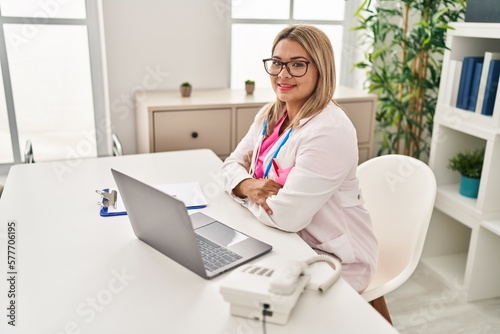 Young hispanic woman wearing doctor uniform working al clinic