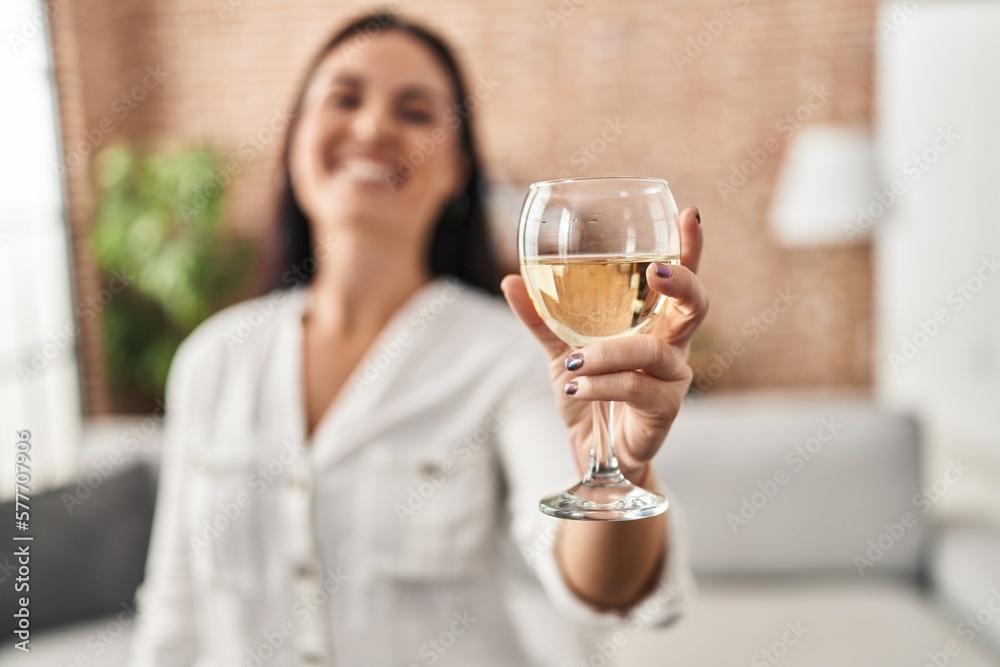 Young beautiful hispanic woman drinking glass of wine standing at home Young beautiful hispanic woman drinking glass of wine standing at home