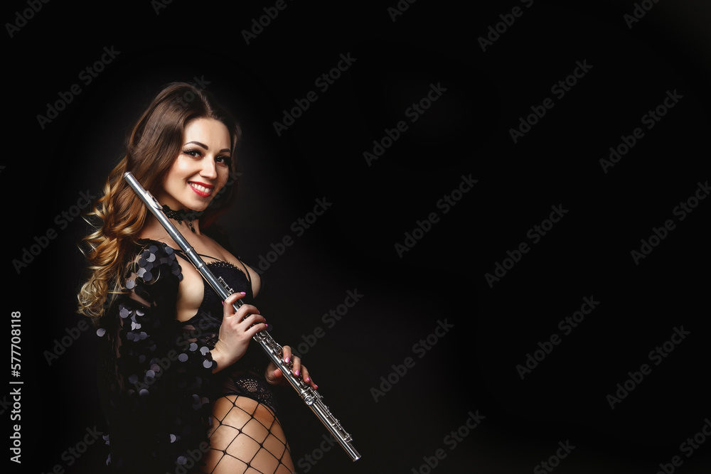 Smiling pretty cover woman posing with flute at black isolated background, looking at camera. Happy chic lady in black dress holding flute in hands. Orchestra music concept. Copy ad text space, banner