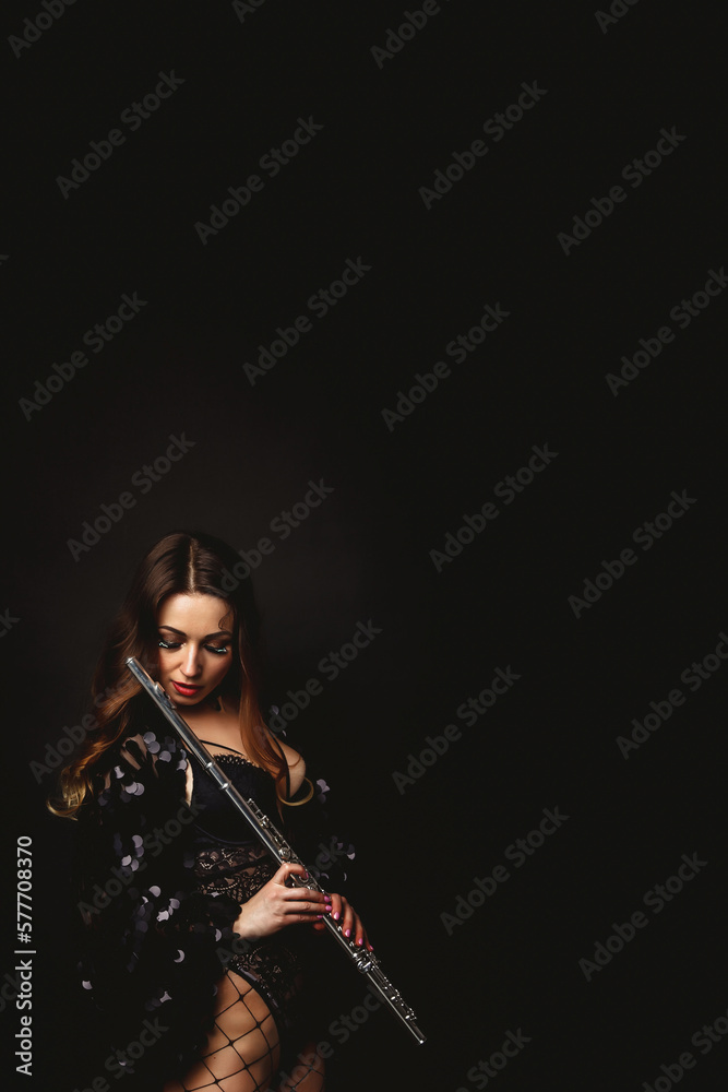 Pensive pretty cover woman posing with flute at black isolated background, closed eyes. Chic lady flautist in black dress holding flute in hands. Orchestra music concept. Copy ad text space, poster