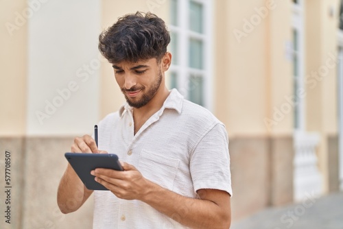 Young arab man drawing on touchpad standing at street