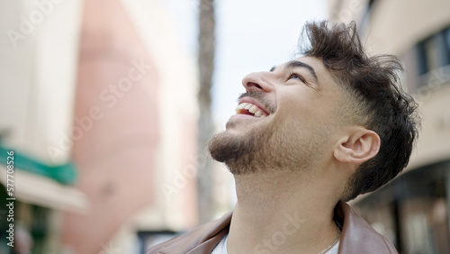 Young arab man smiling confident looking to the sky at street