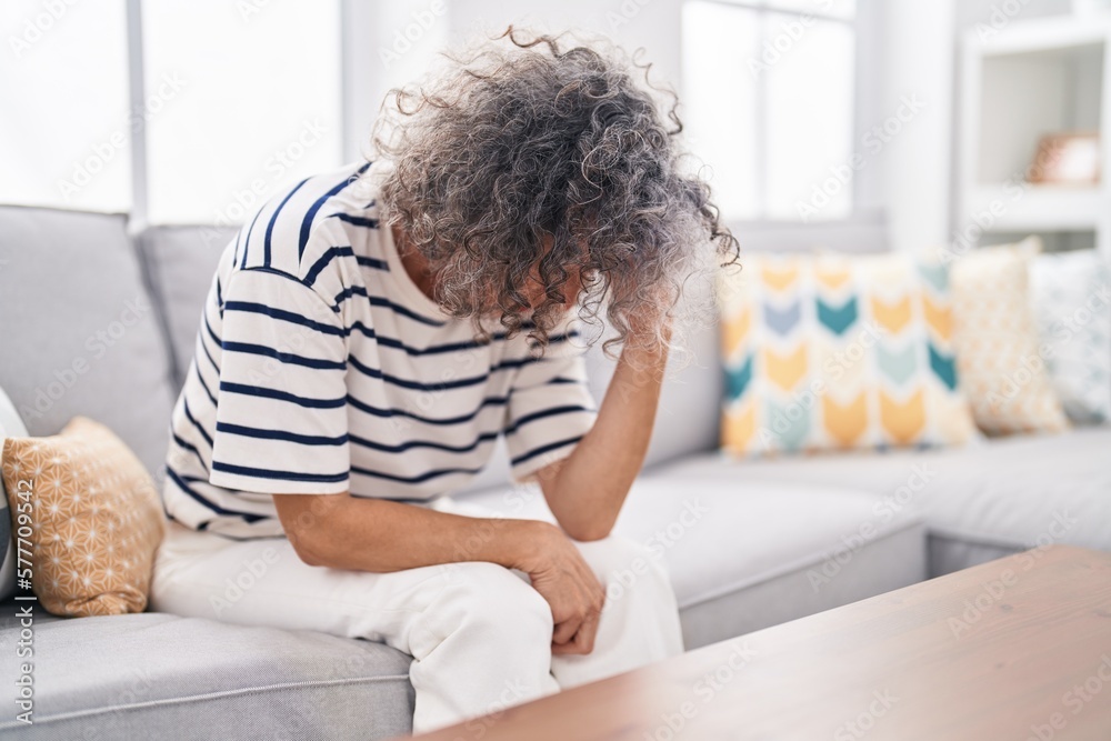 Middle age grey-haired woman stressed sitting on sofa at home Middle age grey-haired woman stressed sitting on sofa at home