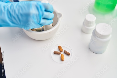 Middle age woman scientist mixing pills on bowl at laboratory photo