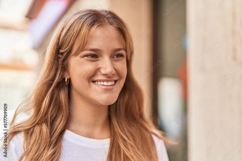 Young blonde girl smiling confident looking to the side at street Young blonde girl smiling confident looking to the side at street