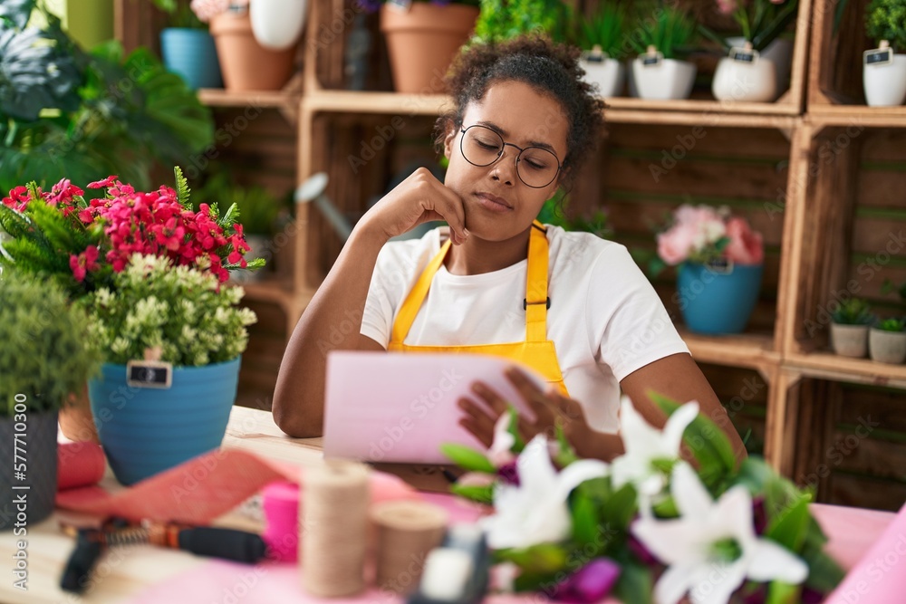 African american woman florist reading document at flower shop