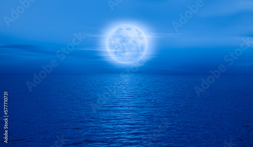 Fototapeta Naklejka Na Ścianę i Meble -  Night sky with blue moon in the clouds over the calm blue sea 
