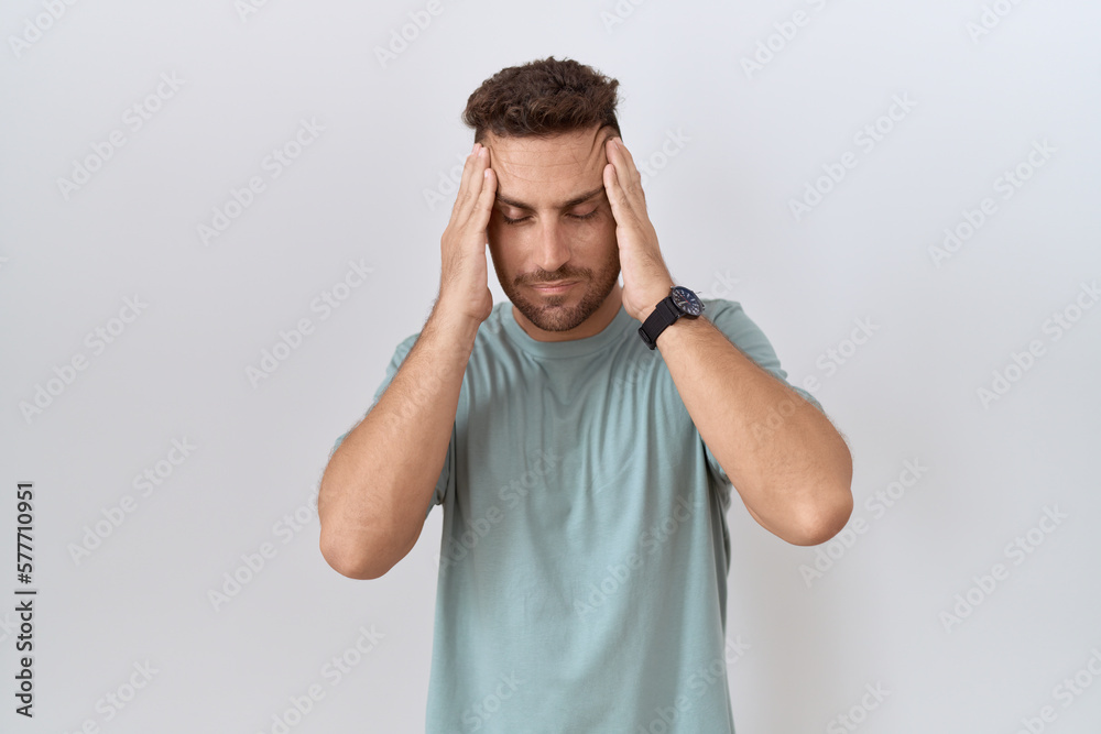 Hispanic man with beard standing over white background with hand on head, headache because stress. suffering migraine. Hispanic man with beard standing over white background with hand on head, headache because stress. suffering migraine.