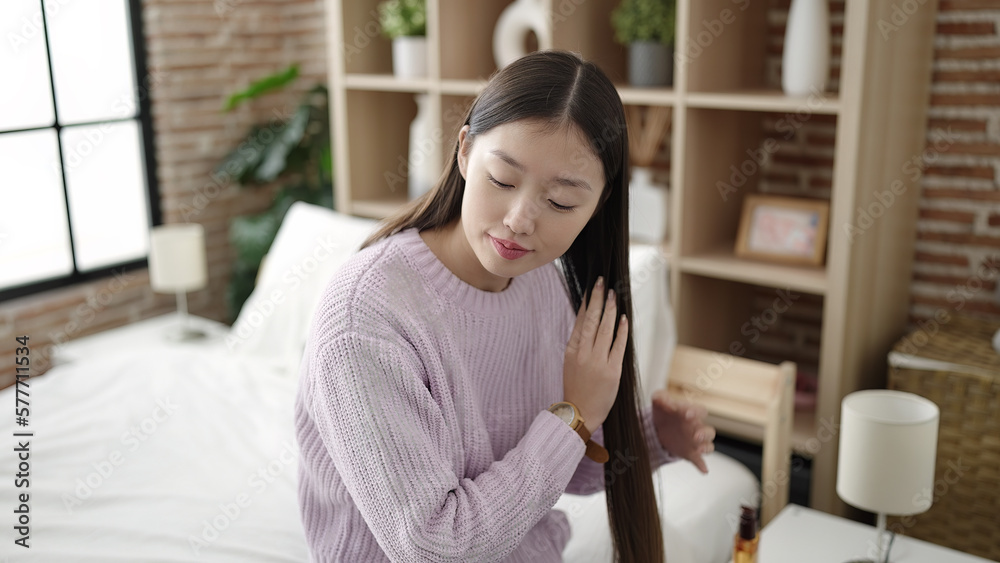 Young chinese woman having hair treatment sitting on bed at bedroom Young chinese woman having hair treatment sitting on bed at bedroom