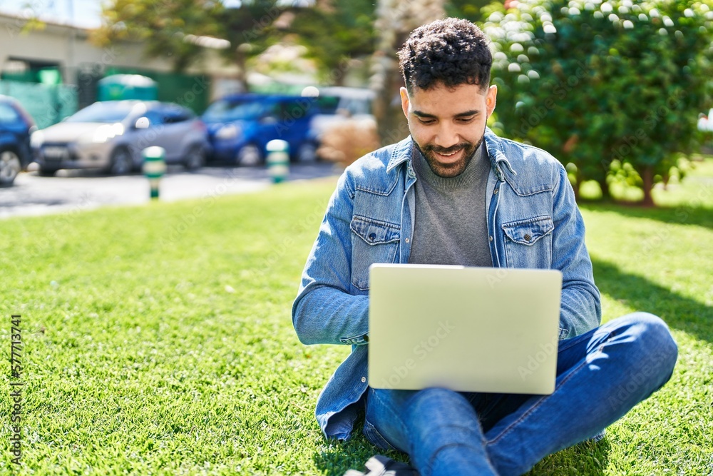 Young hispanic man using laptop sitting on herb at park Young hispanic man using laptop sitting on herb at park