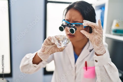 Young chinese woman wearing scientist uniform examining diamond at laboratory