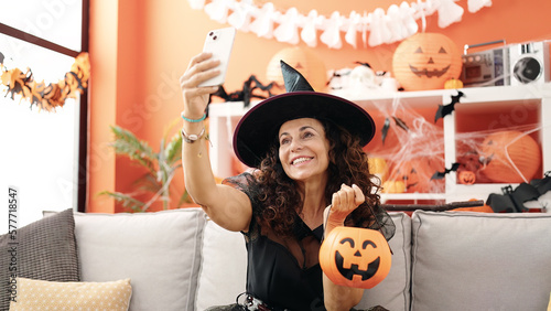 Middle age hispanic woman make selfie by smartphone having halloween party at home