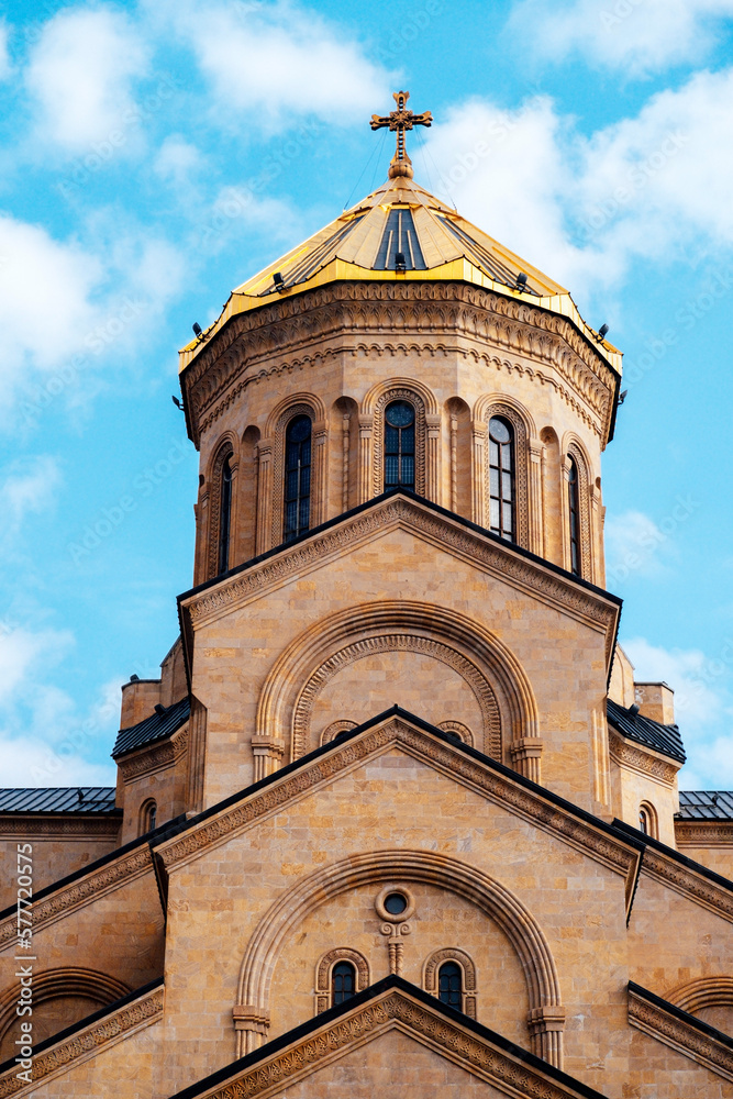 Part of Tsminda Sameba - Holy Trinity Church in Tbilisi, Georgia on a sunny day against a blue sky.