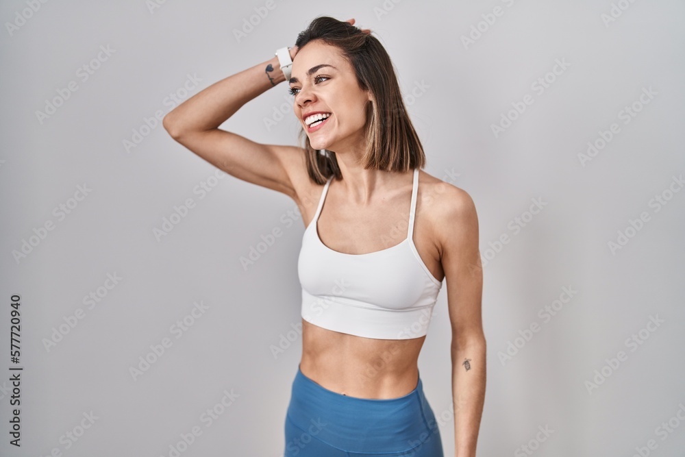 Hispanic woman wearing sportswear over isolated background smiling confident touching hair with hand up gesture, posing attractive and fashionable Hispanic woman wearing sportswear over isolated background smiling confident touching hair with hand up gesture, posing attractive and fashionable