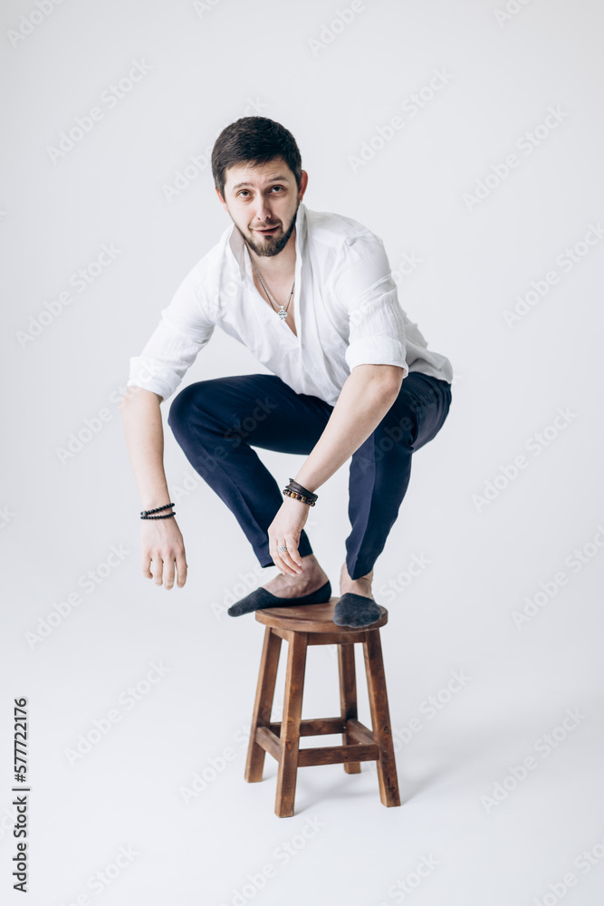 Portrait of a handsome man with a beard in a white shirt sits on a chair Portrait of a handsome man with a beard in a white shirt sits on a chair