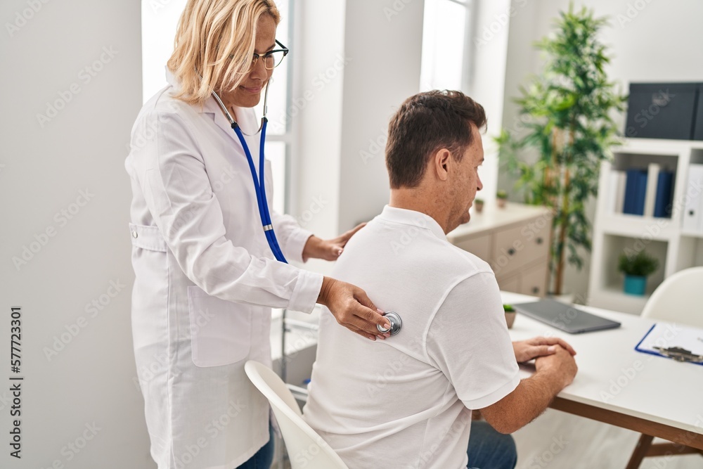 Obraz premium Middle age man and woman doctor and patient examining vision having medical consultation at clinic