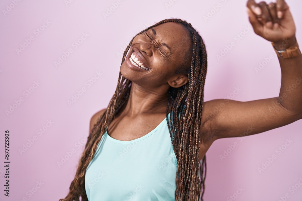 African american woman standing over pink background dancing happy and cheerful, smiling moving casual and confident listening to music African american woman standing over pink background dancing happy and cheerful, smiling moving casual and confident listening to music