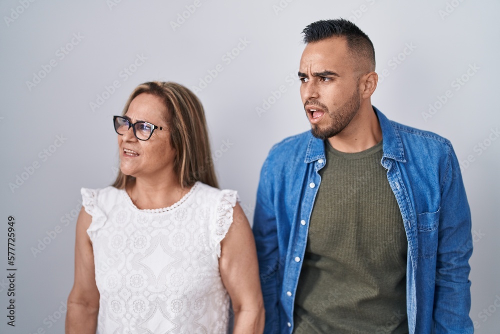 Hispanic mother and son standing together angry and mad screaming frustrated and furious, shouting with anger. rage and aggressive concept. Hispanic mother and son standing together angry and mad screaming frustrated and furious, shouting with anger. rage and aggressive concept.