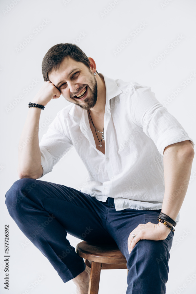 Portrait of a handsome man with a beard in a white shirt sits on a chair Portrait of a handsome man with a beard in a white shirt sits on a chair