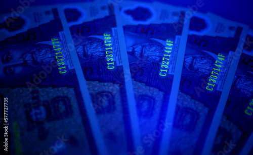 Guatemalan banknotes under UV light. Checking for counterfeit money. Close-up Guatemala quetzales. UV light banknote detector. Fake money testing