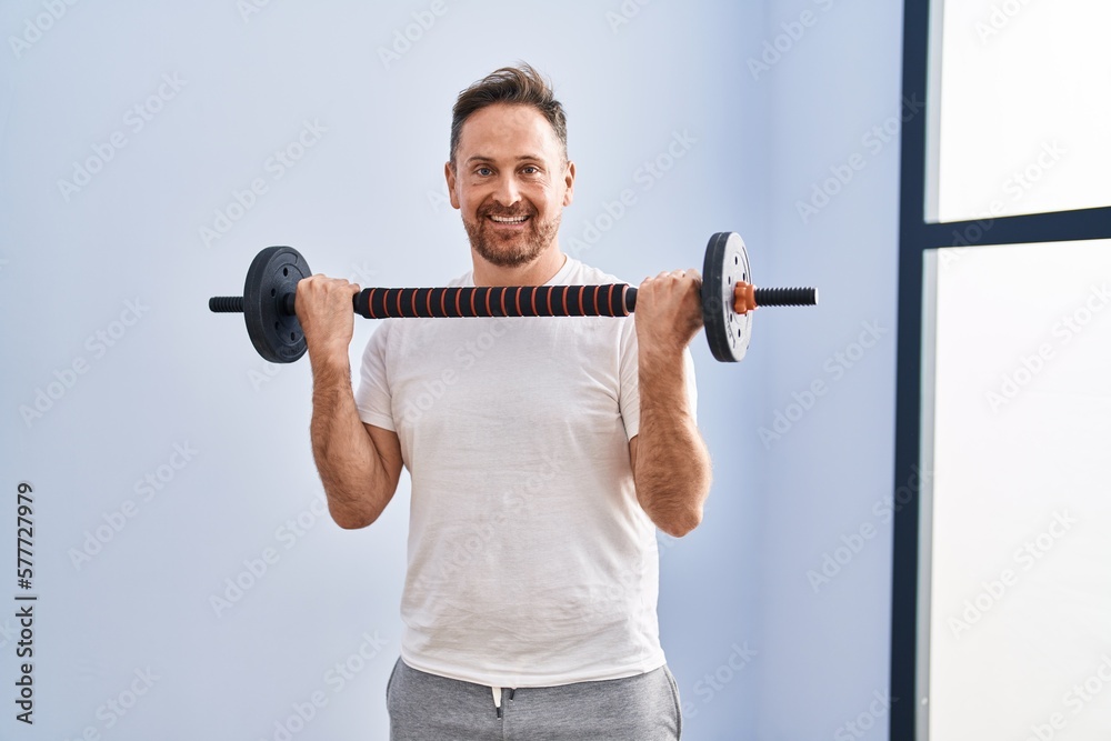 Young caucasian man smiling confident using bar and weight disc at sport center Young caucasian man smiling confident using bar and weight disc at sport center