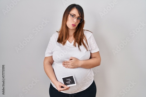 Pregnant woman holding baby ecography depressed and worry for distress, crying angry and afraid. sad expression.