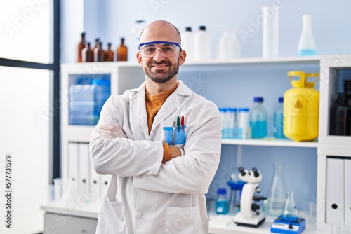 Young man scientist standing with arms crossed gesture at laboratory