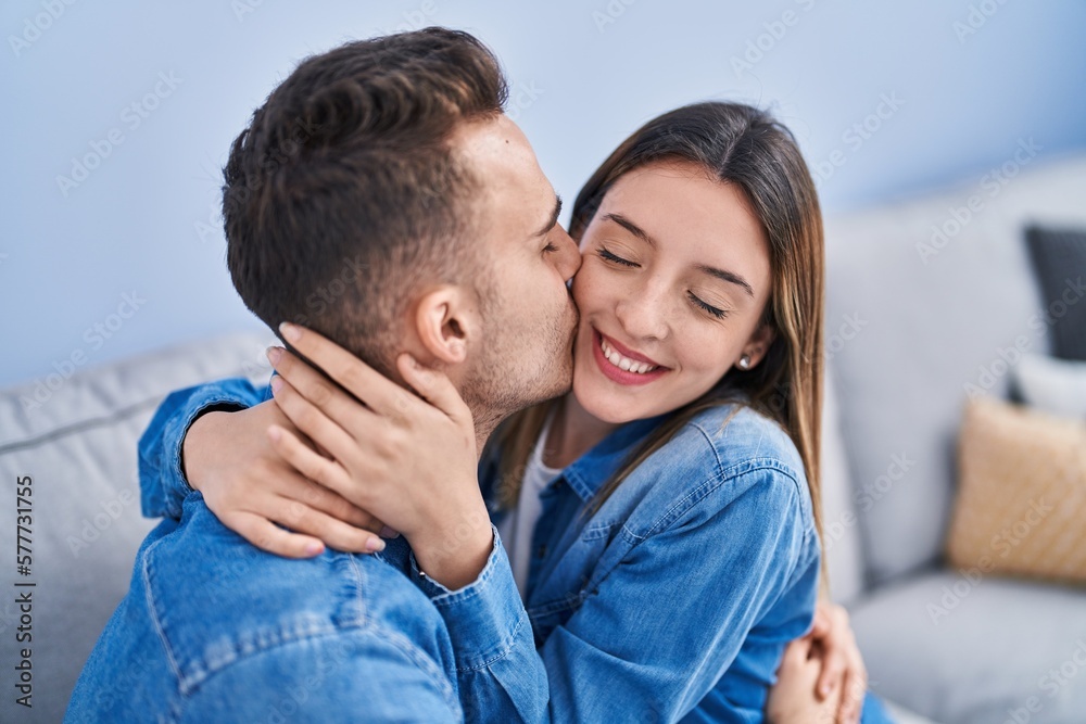 Man and woman couple sitting on sofa hugging each other and kissing at home Man and woman couple sitting on sofa hugging each other and kissing at home