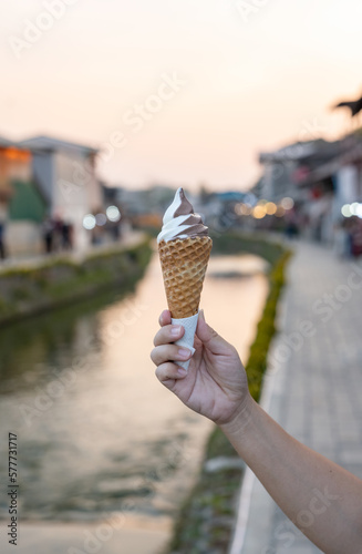 Hand holding ice cream cone, canal background