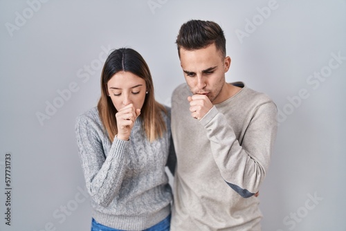 Young hispanic couple standing over white background feeling unwell and coughing as symptom for cold or bronchitis. health care concept. © Krakenimages.com