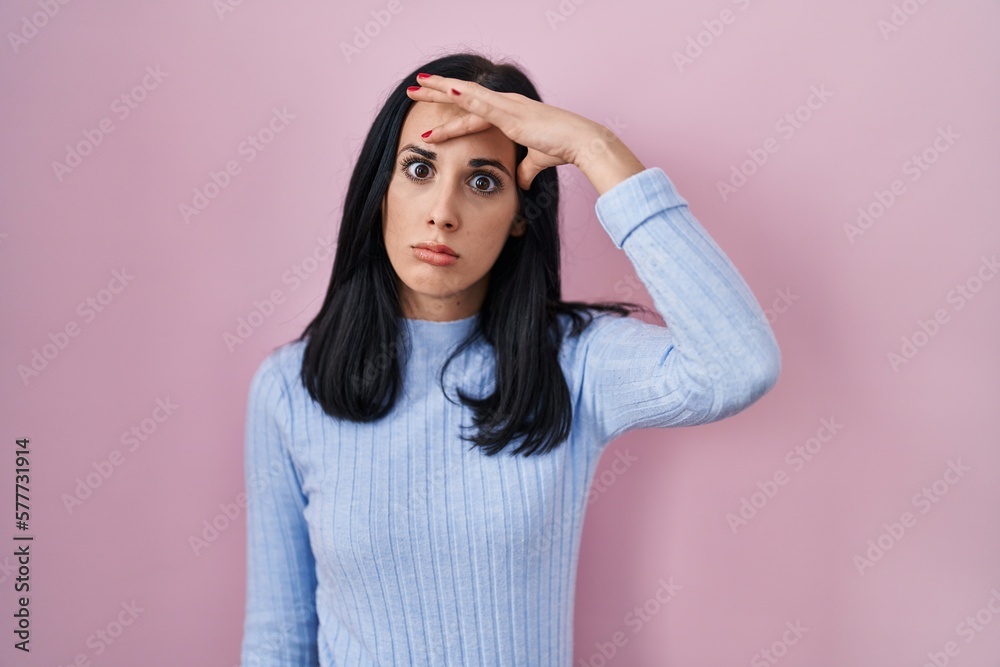 Hispanic woman standing over pink background worried and stressed about a problem with hand on forehead, nervous and anxious for crisis Hispanic woman standing over pink background worried and stressed about a problem with hand on forehead, nervous and anxious for crisis