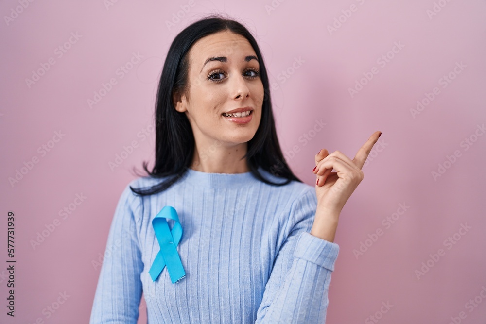 Hispanic woman wearing blue ribbon smiling happy pointing with hand and finger to the side Hispanic woman wearing blue ribbon smiling happy pointing with hand and finger to the side