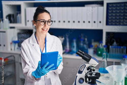 Young caucasian woman scientist smiling confident using touchpad at laboratory