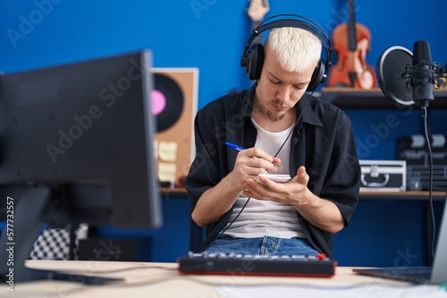 Young caucasian man musician composing song at music studio