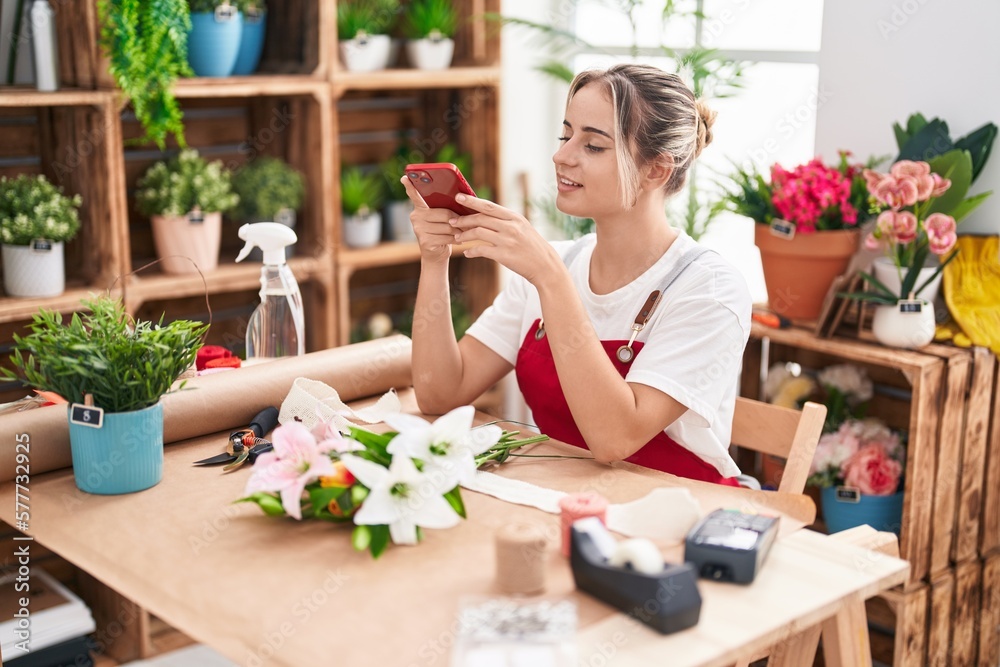 Young blonde woman florist make photo to bouquet of flowers by smartphone at flower shop