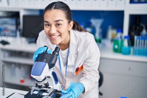 Photographie Young hispanic woman scientist using microscope at laboratory