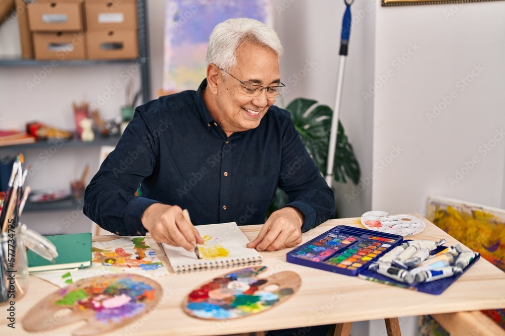 Senior man smiling confident drawing on notebook at art studio Senior man smiling confident drawing on notebook at art studio
