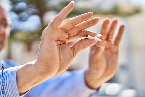 Senior man breaking cigarette at park