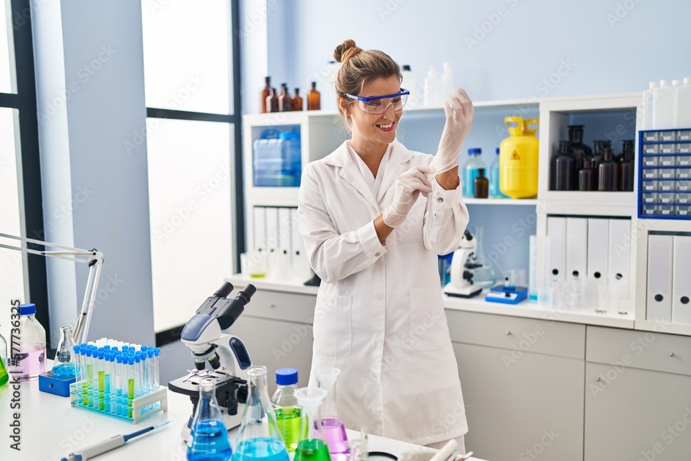 Young blonde woman wearing scientist uniform and gloves at laboratory Young blonde woman wearing scientist uniform and gloves at laboratory