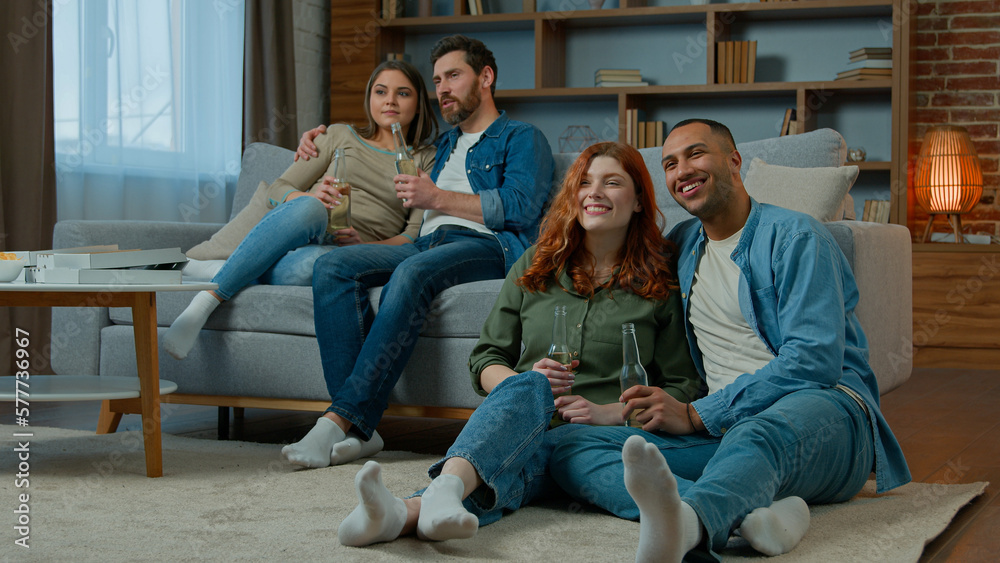 Two ethnic couple diverse men women watch television romantic tv film at home family rest on sofa and floor multiracial friends watching comedy movie comfortable leisure in apartment with bottled beer Two ethnic couple diverse men women watch television romantic tv film at home family rest on sofa and floor multiracial friends watching comedy movie comfortable leisure in apartment with bottled beer