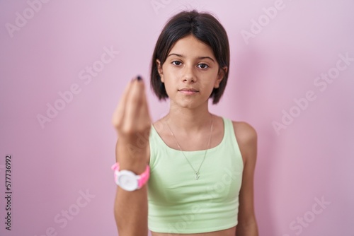 Young girl standing over pink background doing italian gesture with hand and fingers confident expression © Krakenimages.com